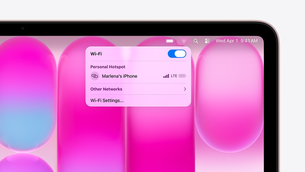 MacBook Neo hajnalpír színben, a Wi-Fi menü Személyes hotspot szakaszában „Marlena iPhone-ja” látszik választható lehetőségként.