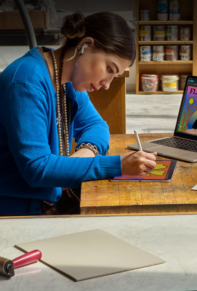 机に向かって、Apple Pencilを使ってiPadで絵を描いている学生