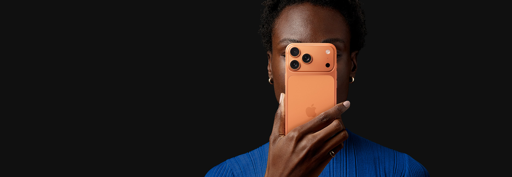 Egy személy egy kozmosznarancs színű iPhone 17 Prót tart az arca előtt, a telefon hátulnézetből látható